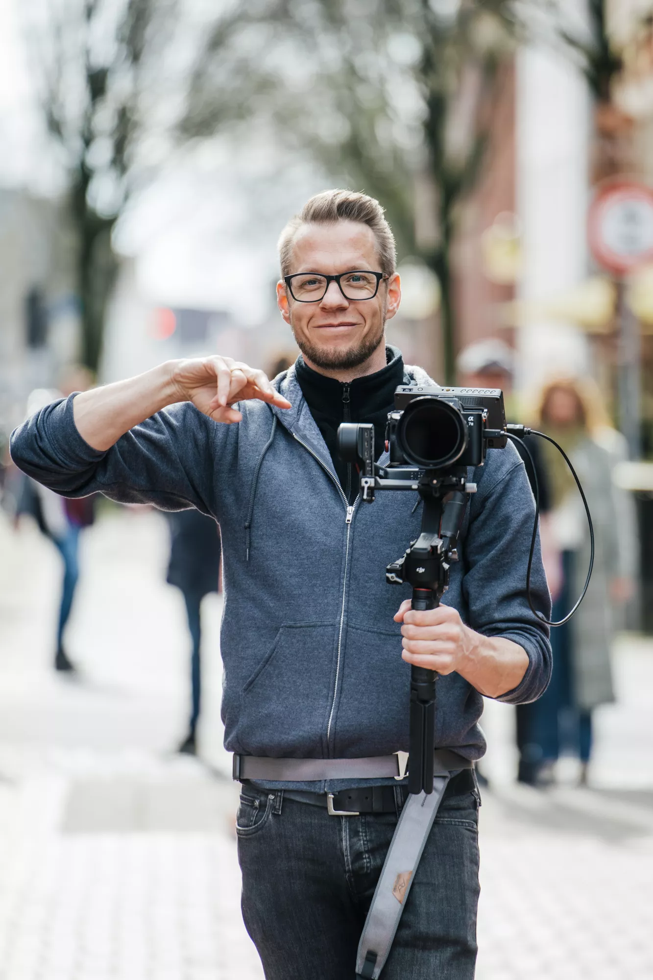 Mann mit Brille und professionellem Kamera-Gimbal in einer urbanen Umgebung